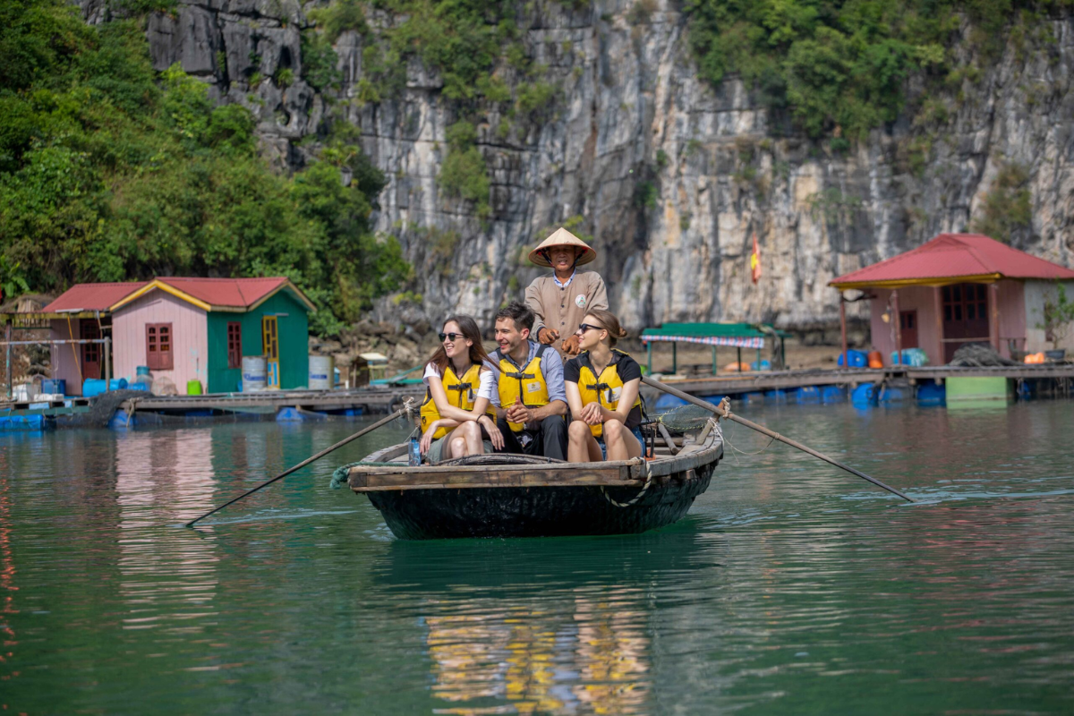 Tourists enjoying a bamboo boat ride through limestone cliffs in Ha Long Bay