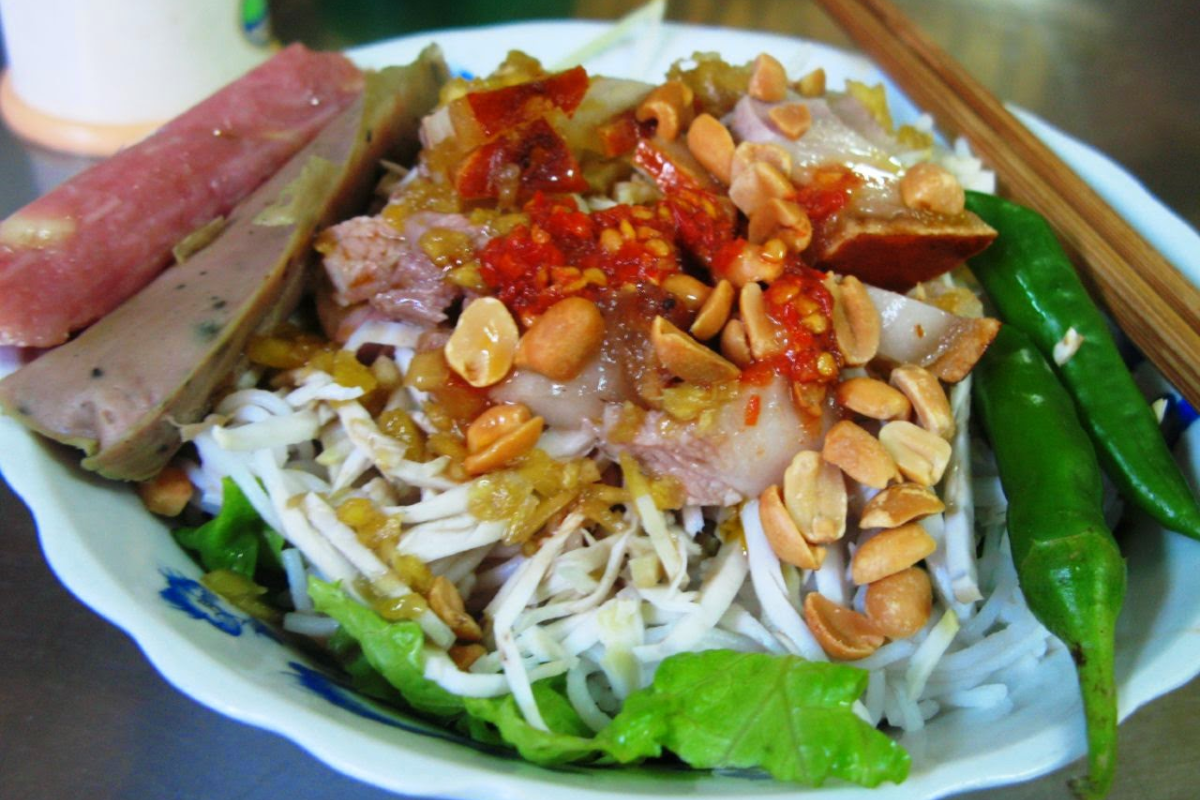 A bowl of Bun Mam Tran Ke Xuong with roasted pork, fresh herbs, and peanuts
