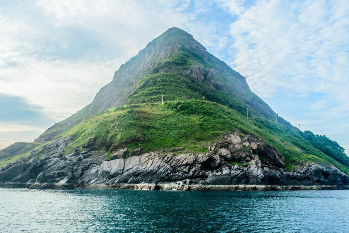Shark fin-shaped headland surrounded by blue water at Ca Map Cape