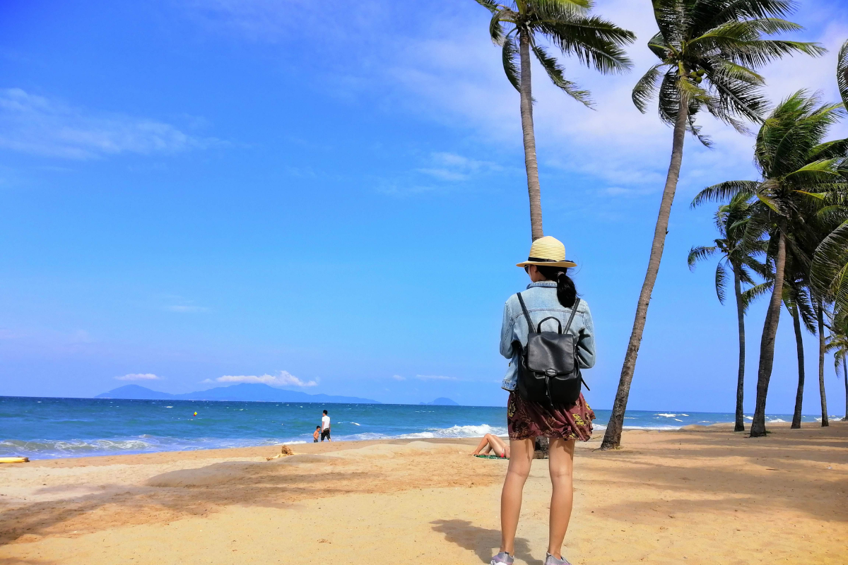 Tourists relaxing on Cua Dai Beach under sunny April skies in Hoi An