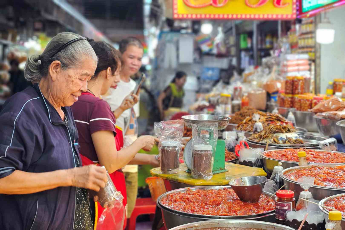Bustling scene inside Dong Ba Market with colorful stalls and local shoppers.