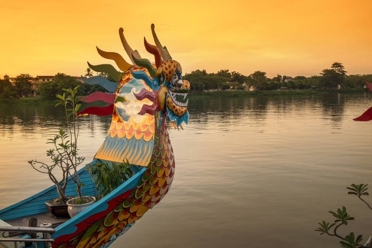 Dragon boat cruising on the Perfume River with Hue landmarks in the background