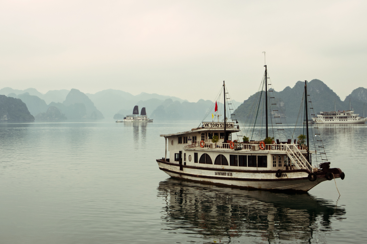 A cruise ship sailing through the misty waters of Ha Long Bay in December