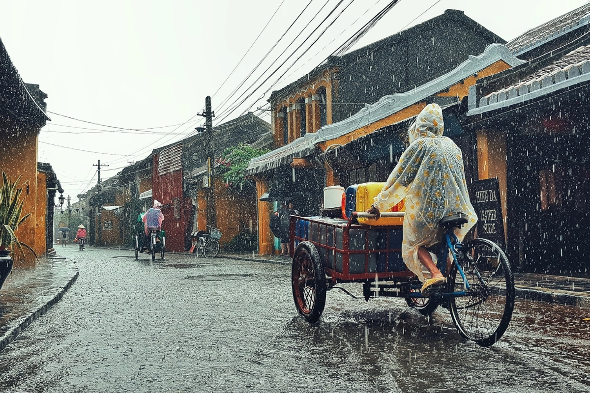 Tourists walking with umbrellas along a lantern-lit street in Hoi An during the rainy season