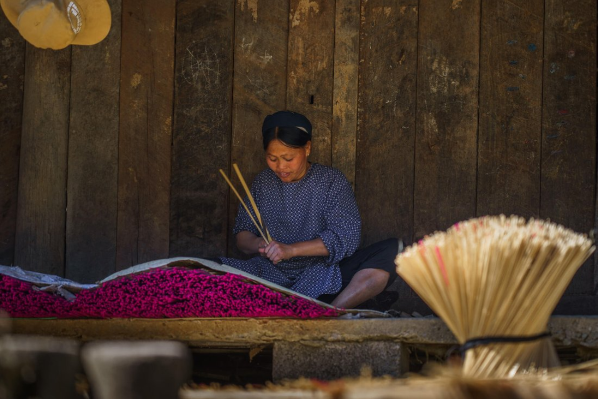 Nung An woman crafting incense by hand in Phia Thap Village