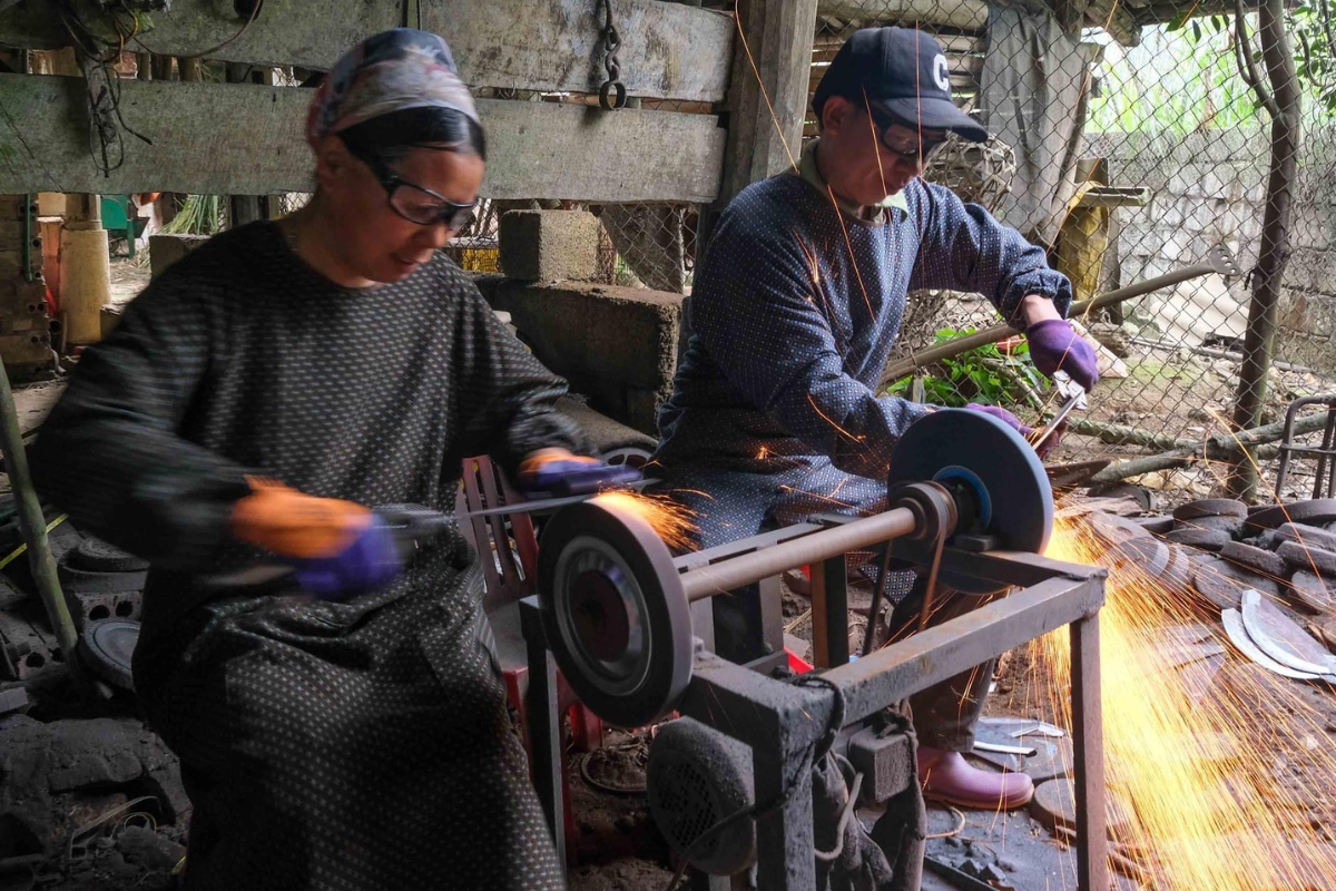 Skilled blacksmith forging metal with traditional tools in Phuc Sen Village