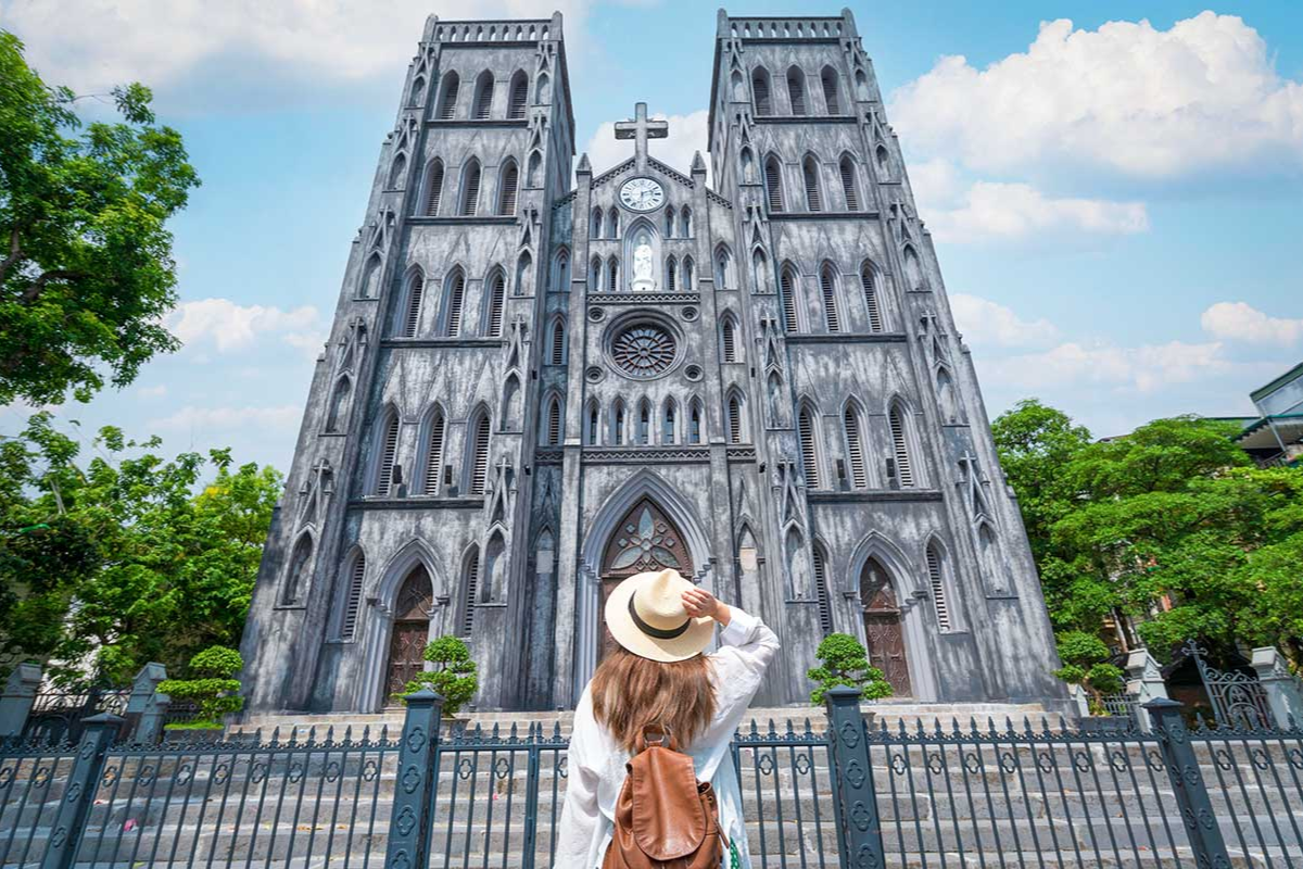 St. Joseph Cathedral in Hanoi with tall Gothic spires and tourist in front