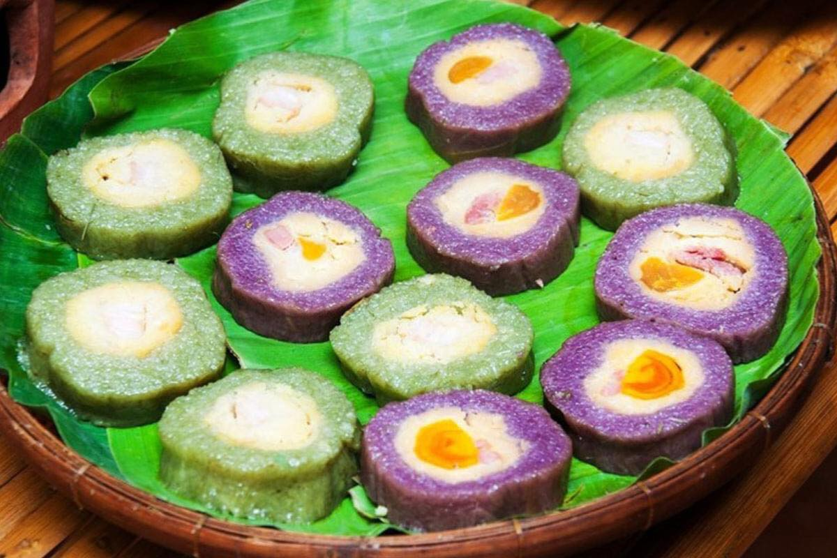 Bánh Tét Mật Cật wrapped in honey plant leaves, sliced to reveal sticky rice and filling