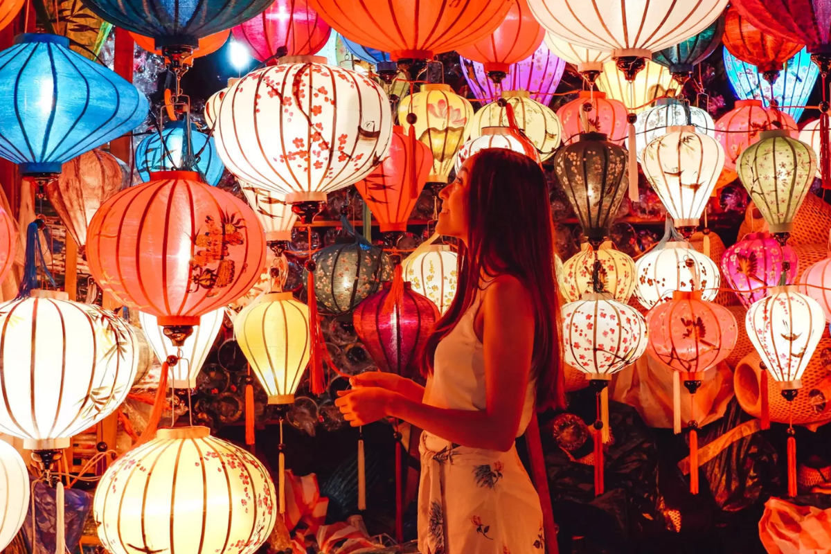 Tourists walking through Hoi An Ancient Town with colorful lanterns overhead