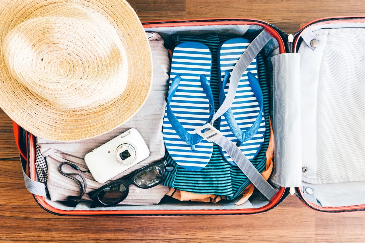 Travel essentials for a summer trip to Ha Long Bay including sunscreen, hat, and swimwear