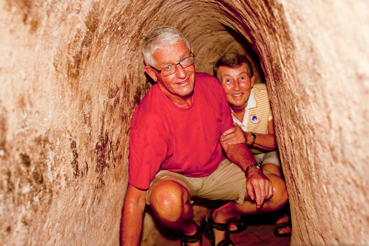 Tourist entering a narrow tunnel entrance at Cu Chi