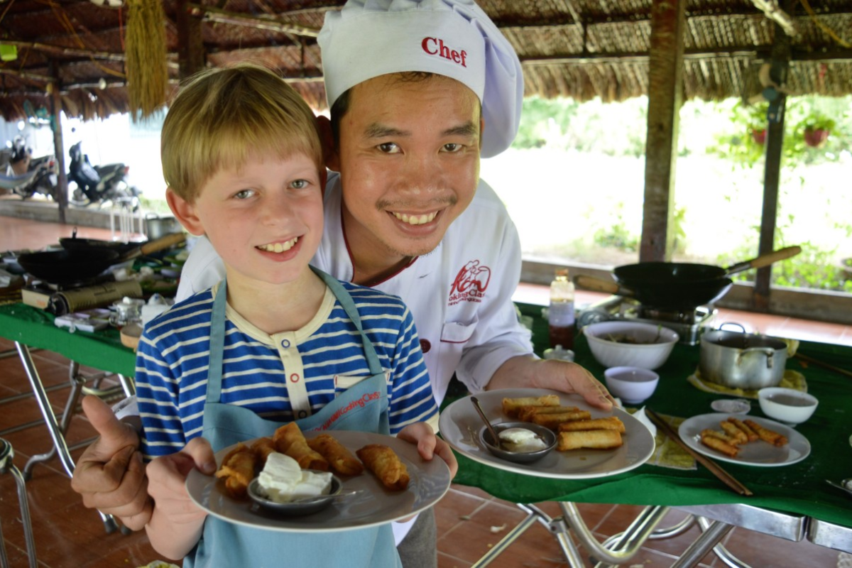 Family enjoying a Vietnamese cooking class, preparing spring rolls with a local chef