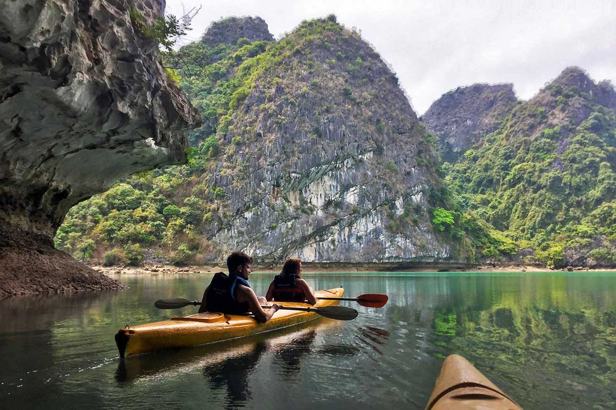 Kayakers exploring sea caves under sunny skies in Ha Long Bay in April
